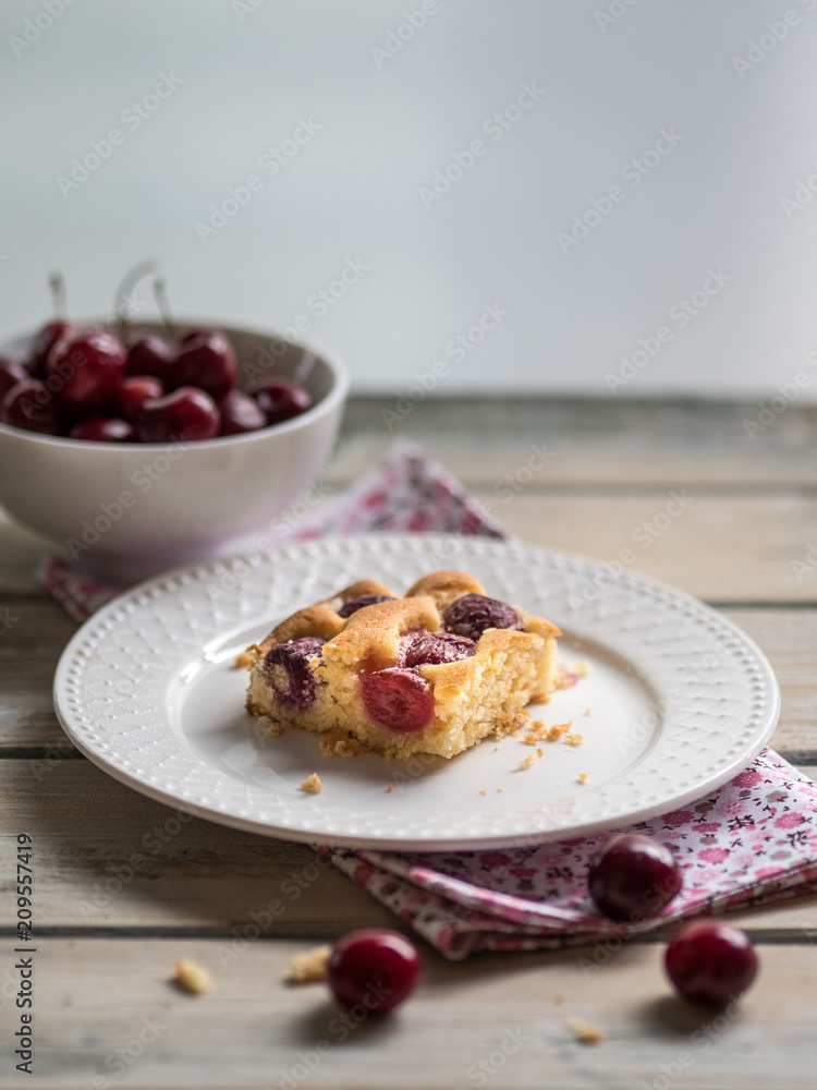 Cherry sponge cake and white ceramic bowl of fresh cherries on white rustic wooden table. Cherry sponge cake and white ceramic bowl of fresh cherries on white rustic wooden table.