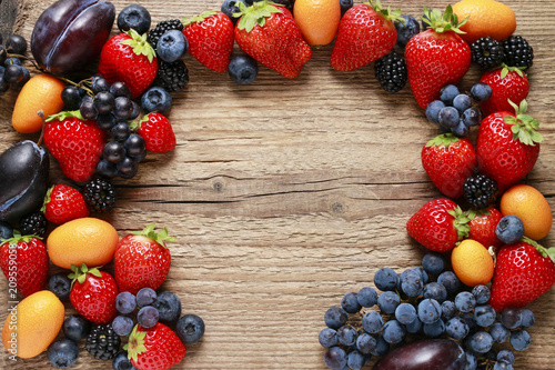 Fototapeta Naklejka Na Ścianę i Meble -  Delicious fruits: strawberry, grape, kumquat, blueberry and blackberry, on wooden background