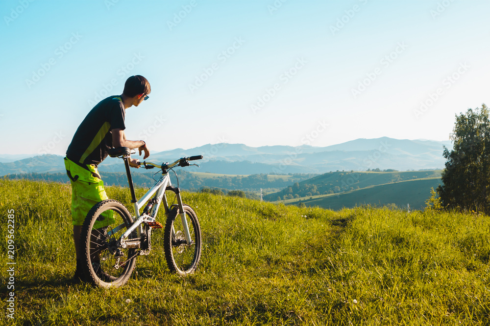 A cyclist on a mountain bike rises uphill. And looks at the scenic landscape.