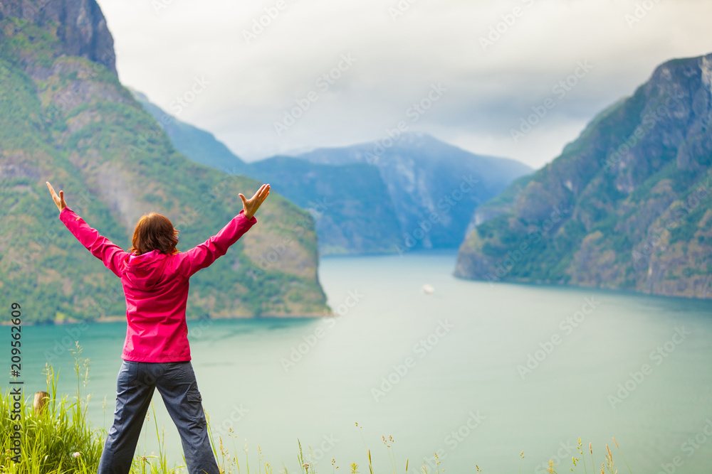 Naklejka premium Woman with raised hands in norwegian mountains fjords