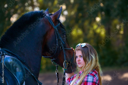 Beautiful girl with long hair on a walk with a horse. Summer cool evening.