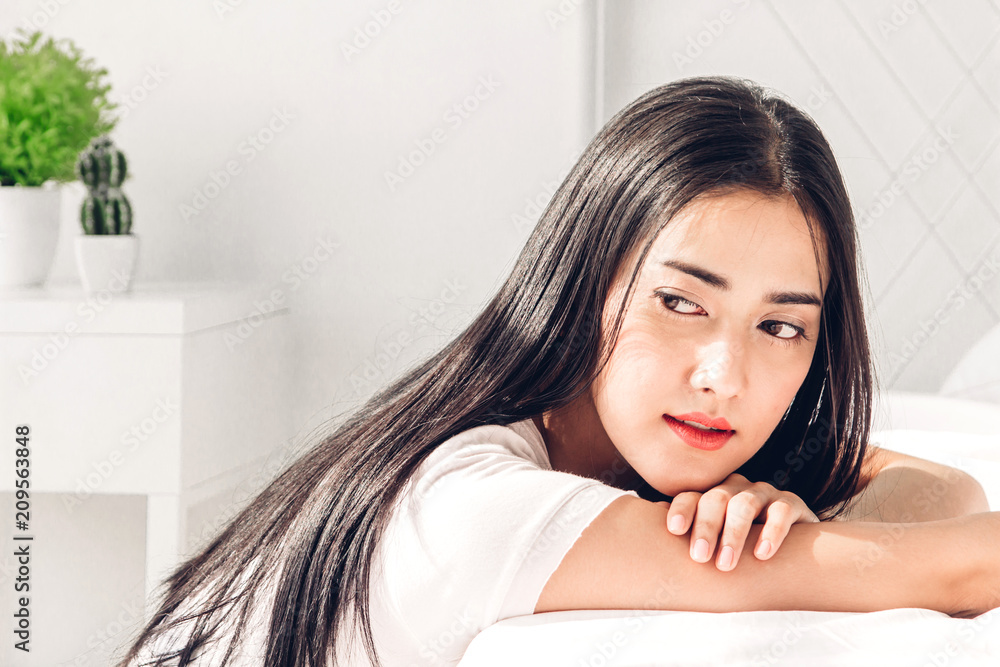 Beautiful woman relaxing on the bed in her room at home