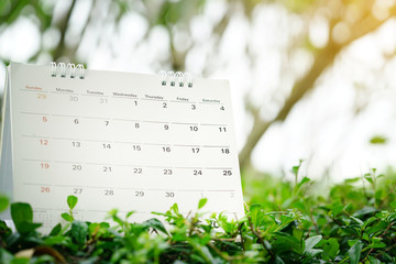 close up of calendar on green nature background with copy space, planning for business meeting or travel planning concept
