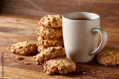 White porcelain mug of tea and sweet cookies on wooden background, top view, selective focus