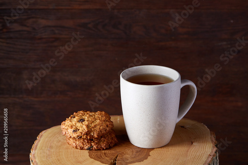 Fototapeta Naklejka Na Ścianę i Meble -  White porcelain mug of tea and sweet cookies on wooden background, top view, selective focus