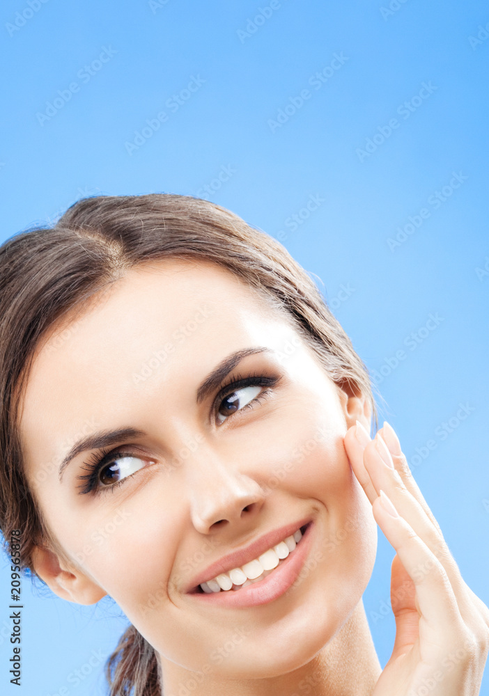 Woman touching skin or applying cream, over blue