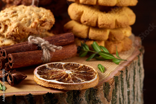 Conceptual composition with assortment of cookies and cinnamon on a wooden barrel, selective focus, close-up