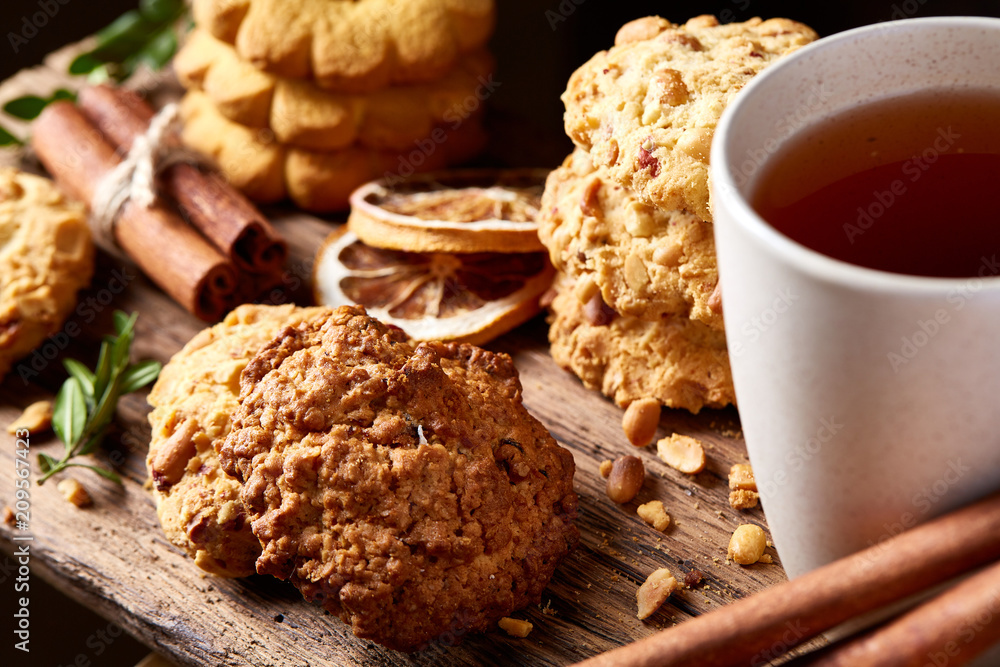 Conceptual festive composition with a cup of hot tea, cookies and spicies on a wooden barrel, selective focus, close-up Conceptual festive composition with a cup of hot tea, cookies and spicies on a wooden barrel, selective focus, close-up