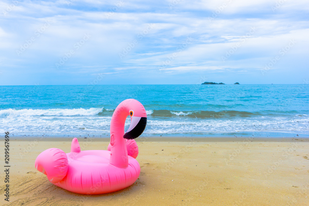 Flamingo raft on the beach in front of blue sea and white sky and foot print Flamingo raft on the beach in front of blue sea and white sky and foot print