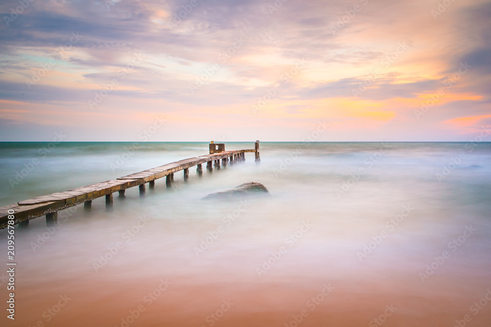 Naklejka premium Long exposure shot of the ocean and a pier in a sunset in Phu Quoc Vietnam.