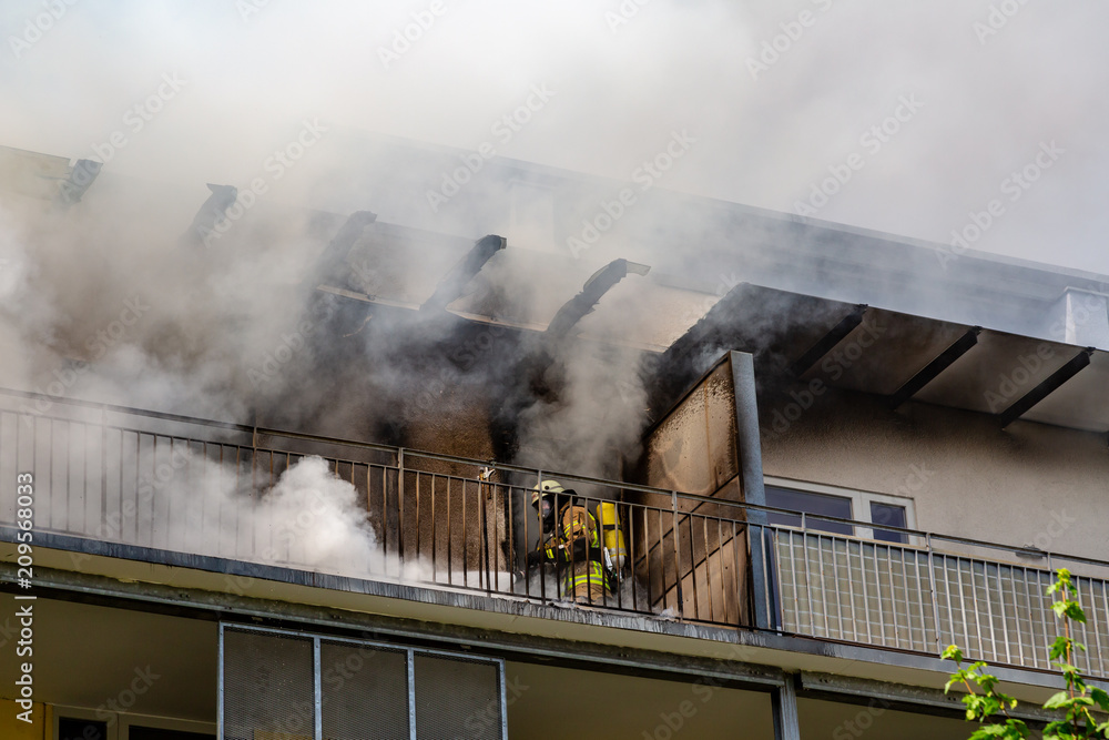 ein Feuerwehrmann versucht ein Wohnungsbrand in einem Hochhaus zu löschen