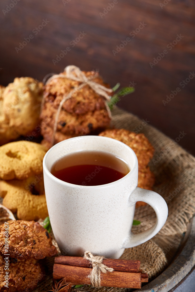 Conceptual festive composition with a cup of hot tea, cookies and spicies on a wooden barrel, selective focus, close-up Conceptual festive composition with a cup of hot tea, cookies and spicies on a wooden barrel, selective focus, close-up