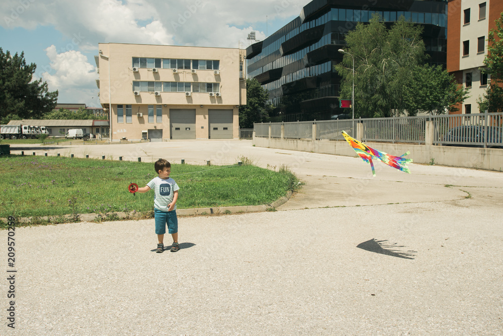 Young boy playing with kite in the school yard on a sunny day