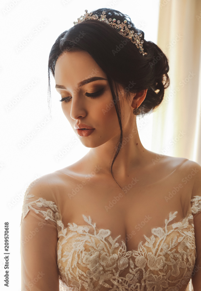 Fototapeta premium beautiful bride in elegant wedding dress and diadem posing in room in the wedding morning