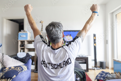 German fan sits in a Deutschland ( Germany ) jersey in front of a television photo