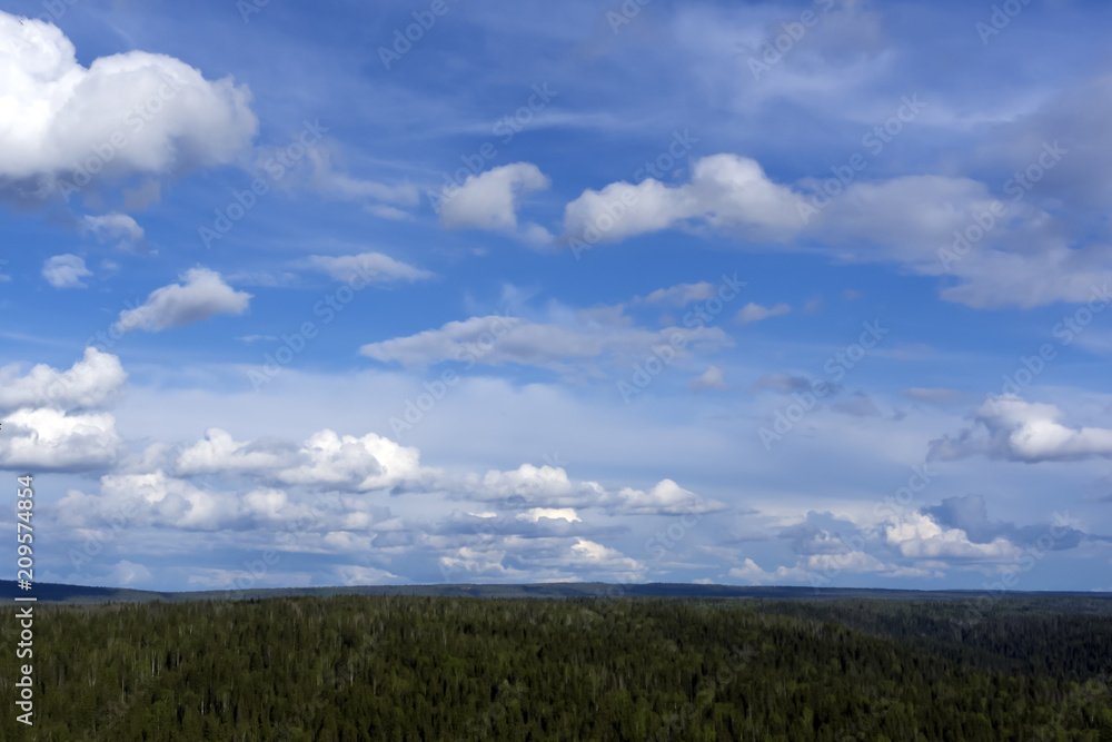 heavenly landscape - a blue sky with clouds over a wooded hilly land with a bird's eye view heavenly landscape - a blue sky with clouds over a wooded hilly land with a bird's eye view