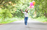 Young hipster girl holding balloon walk on the road,