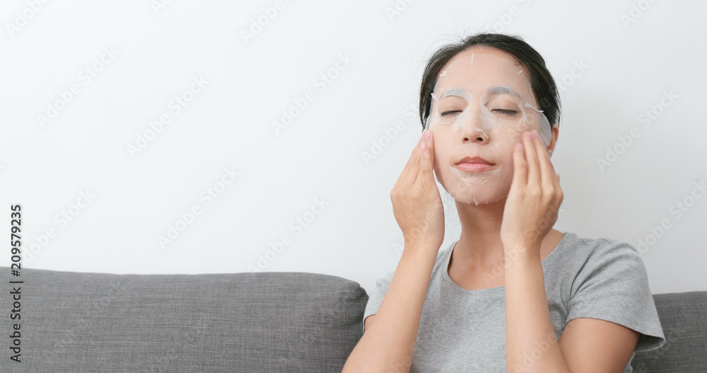 Woman apply paper mask on face Woman apply paper mask on face