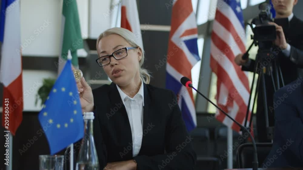 Woman from United Kingdom deputy giving speech about bitcoin while sitting at table in international meeting Woman from United Kingdom deputy giving speech about bitcoin while sitting at table in international meeting