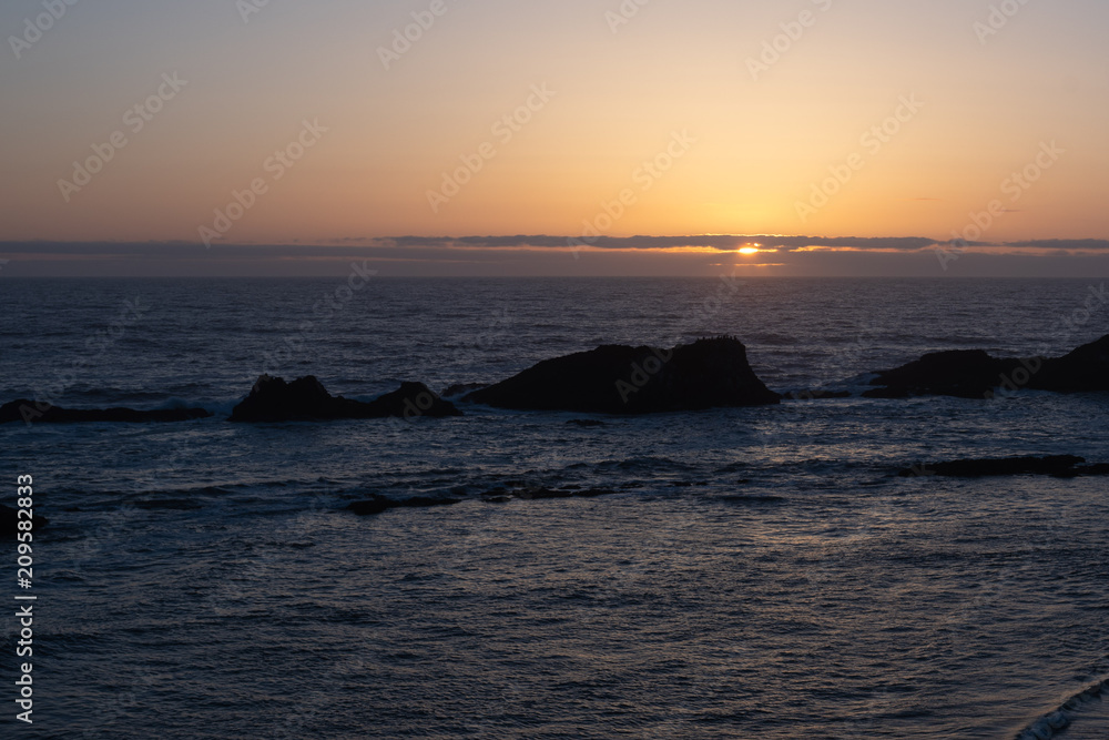 Sunset over pacific ocean with rocks in the water. Yachts, Oregon