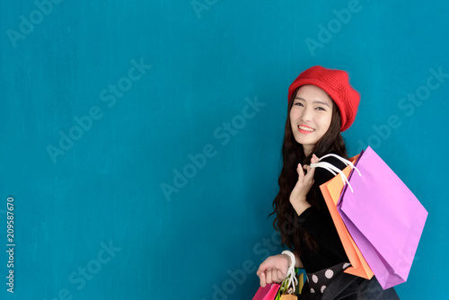 Asian portrait girl has happy and smiling with shopping colorful bags and isolated on green background.