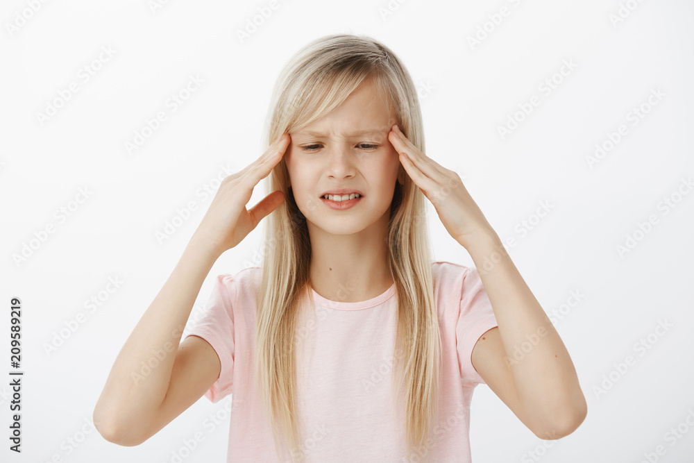 Unfocused worried kid cannot think clearly and hold information in mind. Concerned confused young girl with blond hair, holding hands on temples and grimacing, trying to remember something Unfocused worried kid cannot think clearly and hold information in mind. Concerned confused young girl with blond hair, holding hands on temples and grimacing, trying to remember something