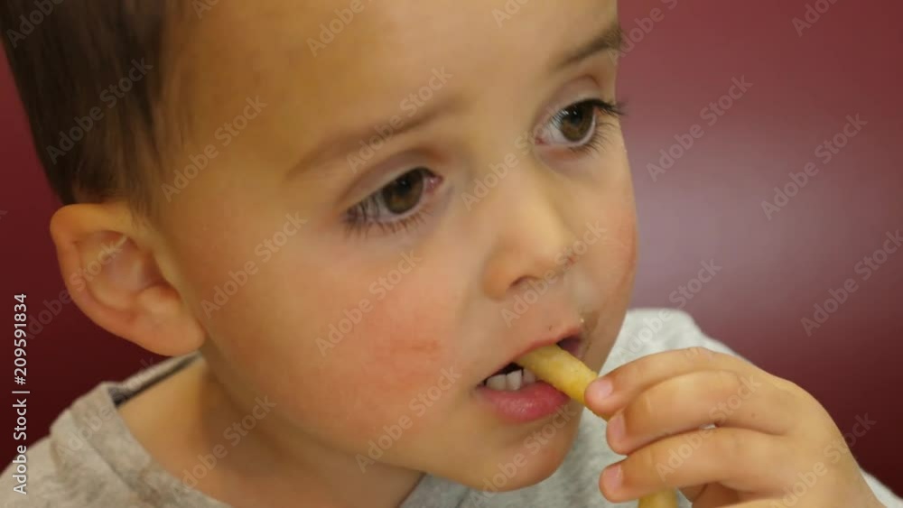 Slow motion boy eating his unhealthy french fries in fast food restaurant Slow motion boy eating his unhealthy french fries in fast food restaurant