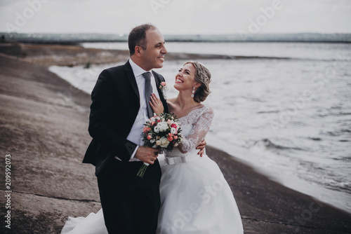 Happy bride and groom walk by the beach photo