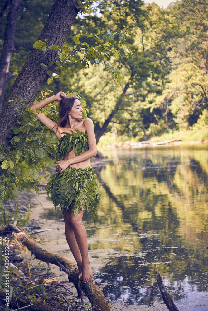 Summer heat. Beautiful young girl in a forest lake, open clothes from fern leaves, perfectly combined with nature. A person in the form of a fantasy elf, dryads, cosplay of a character. Summer heat. Beautiful young girl in a forest lake, open clothes from fern leaves, perfectly combined with nature. A person in the form of a fantasy elf, dryads, cosplay of a character.