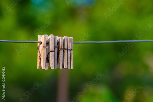 Wooden clothespins hanging on a steel wire on a dark background photo