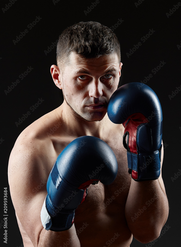 Low key studio portrait of handsome muscular fighter practicing boxing on dark blurred background Low key studio portrait of handsome muscular fighter practicing boxing on dark blurred background