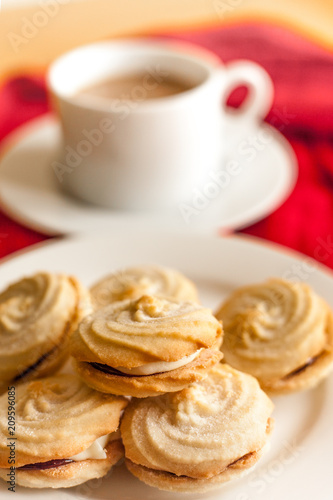 Shortbread swirls with raspberry jam and creme filling with a white cup in the background