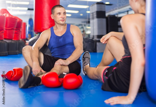Female boxer is sitting with man and talking about healthy in gym. © JackF