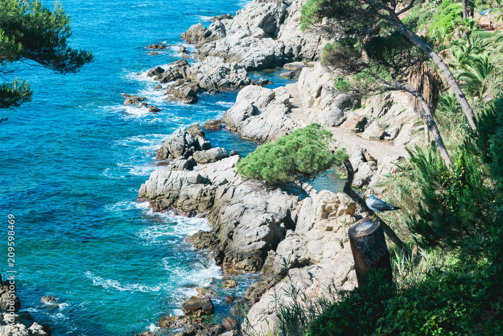 Sea view in Spain. Costa Brava holidays. Blue waves and rocks. Summertime beach.