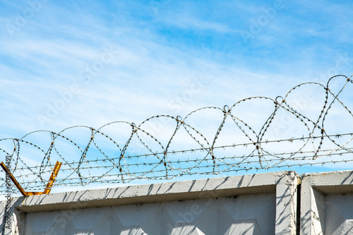 Barbed wire on the high wall on top secret territory