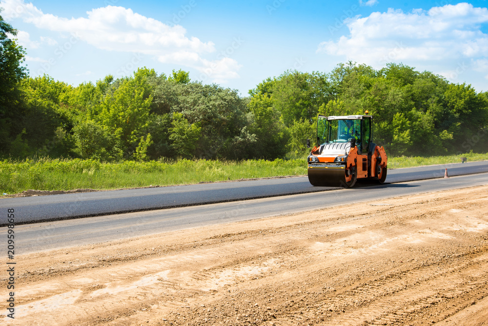 industrial landscape with rollers that rolls a new asphalt on the road. Repair work, complicated transport movement.