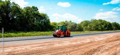 industrial landscape with rollers that rolls a new asphalt on the road. Repair work, complicated transport movement.