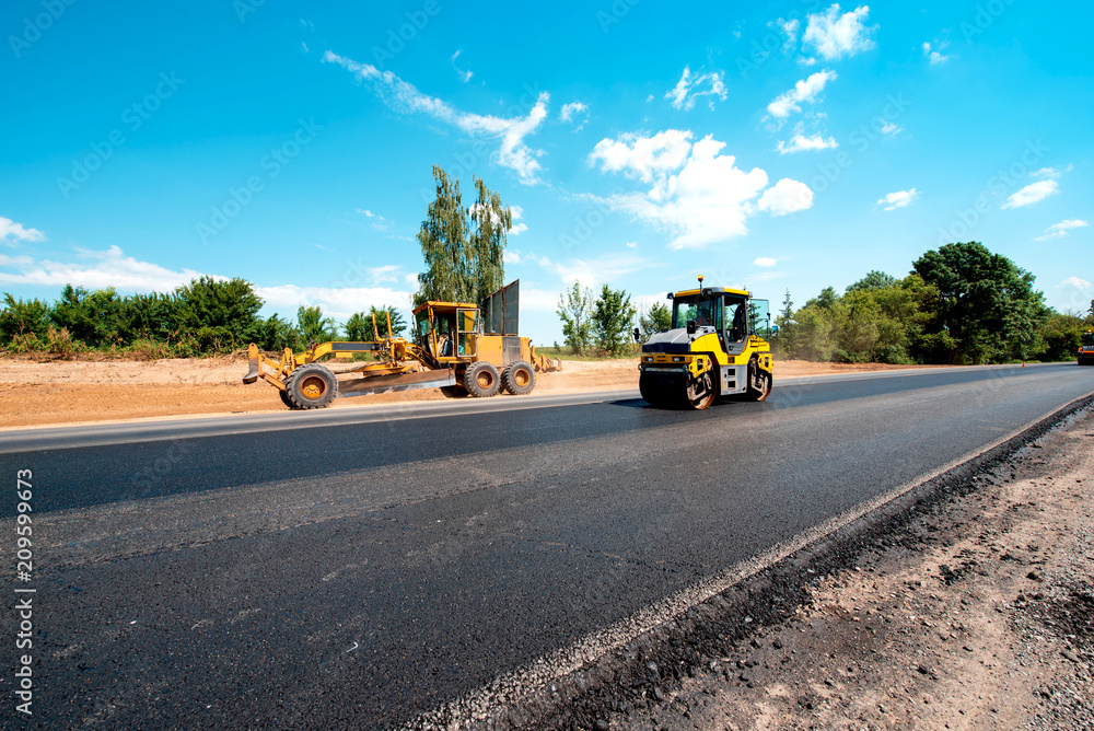 industrial landscape with rollers that rolls a new asphalt in the roadway. Repair, complicated transport movement.