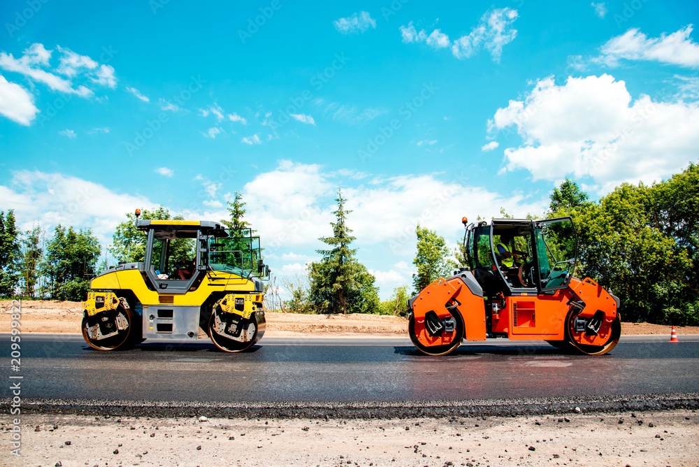 industrial landscape with rollers that rolls a new asphalt in the roadway. Repair, complicated transport movement.