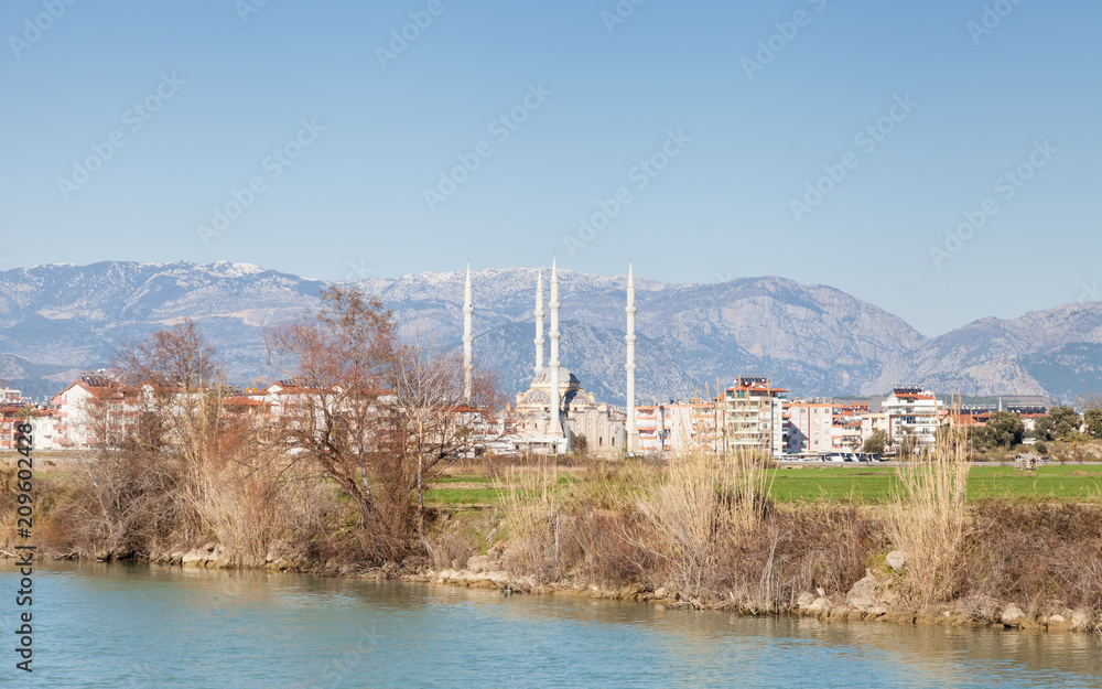 Manavgat River.  The view looking across Manavgat River towards the town of Manavgat in the province of Antalya, southern Turkey.  Kulliye mosque, with its four minarets dominates the skyline.