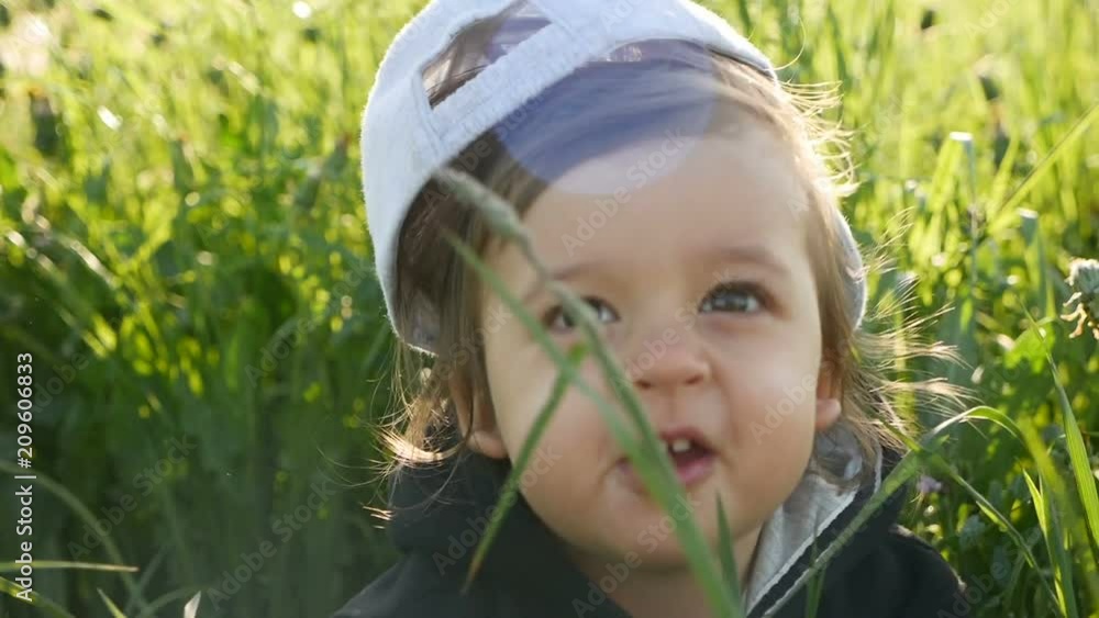 baby boy standing with dandelion in a green field in summer baby boy standing with dandelion in a green field in summer