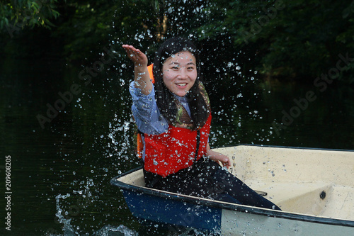 Asian happy girl splashing water sitting in a boat