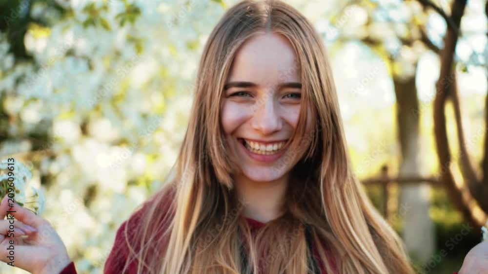 Pretty Ukrainian girl with nice smile hiding face behind flowering twigs. Attractive young Caucasian woman with long hair looking at camera. Springtime. Countryside. Pretty Ukrainian girl with nice smile hiding face behind flowering twigs. Attractive young Caucasian woman with long hair looking at camera. Springtime. Countryside.