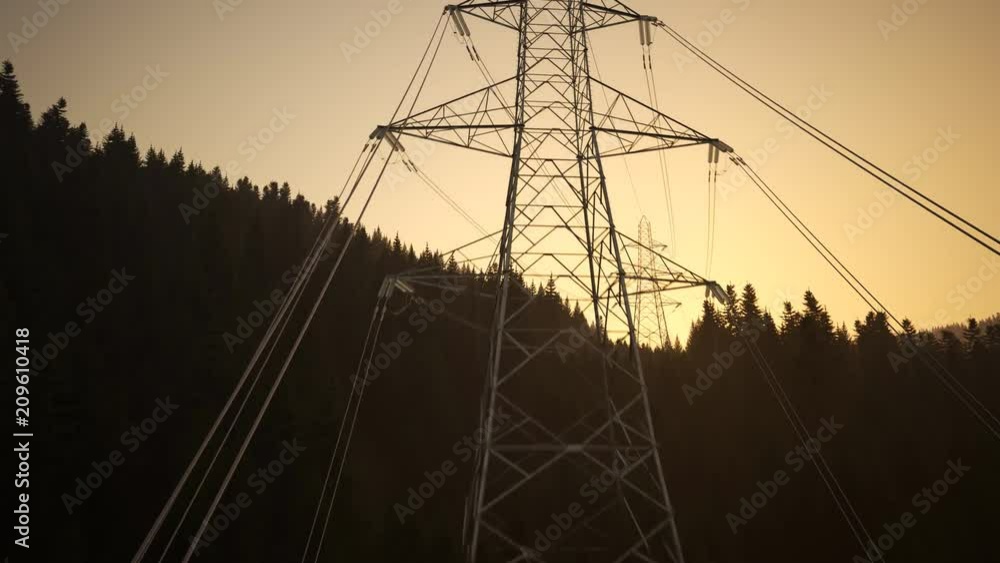 High voltage electricity pylons in a mountain forest during sunset. 4k