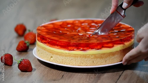 Cutting a piece of strawberry cake with jelly.
