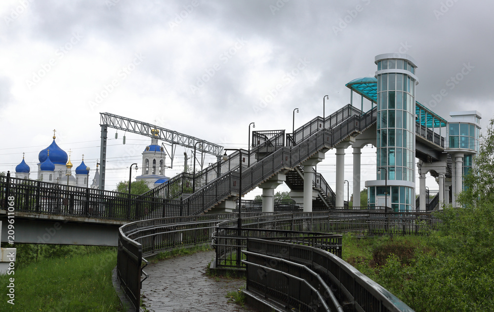 Naklejka premium BOGOLYUBOVO, RUSSIA - MAY 19, 2018: Bridge at railway station on a cloudy day. Vladimir region 