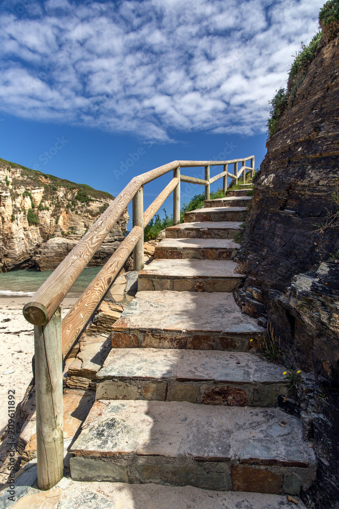 Stone ladder with a wooden handrail along the rock