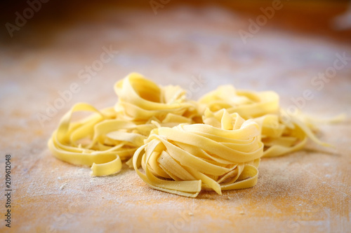 fresh fettuccine pasta on a wooden table with flour