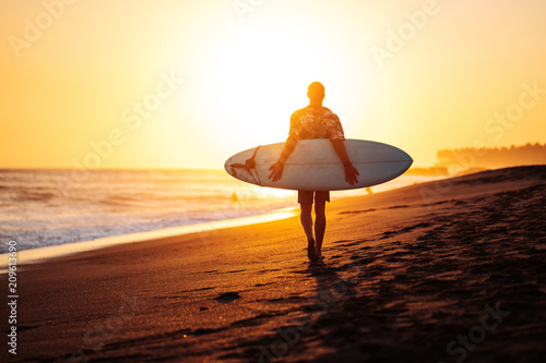 Photography Portrait of happy surfer in hawaiian t-shirt walking with surf board on the beac