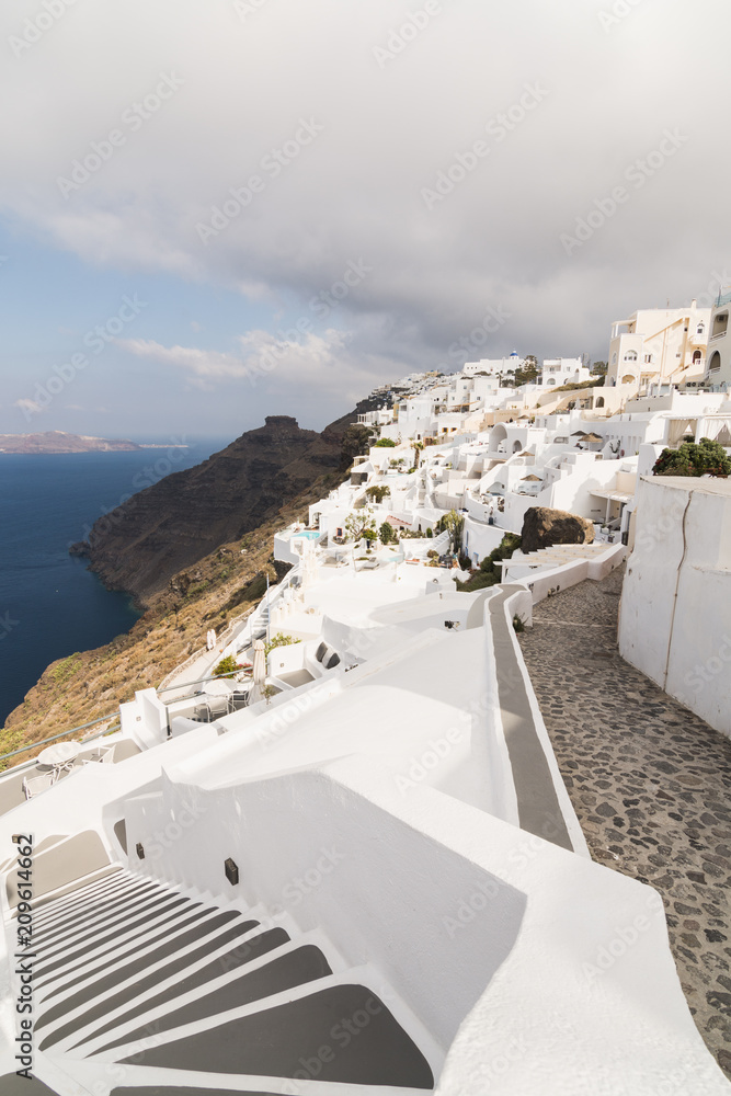 View over Aegean sea, Firostefani village and volcano caldera with luxury hotel on the foreground. Vertical orientation